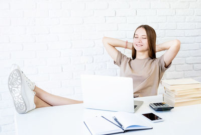 Midsection of woman sitting on table against wall