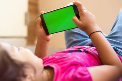 Midsection of woman holding mobile phone at home