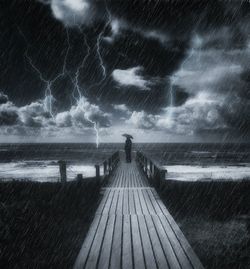 Pier on sea against cloudy sky