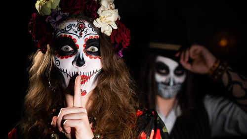 Woman in santa muerte costume and man in skeleton bodypainting for halloween