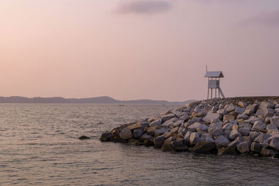 Rocks by sea against sky during sunset