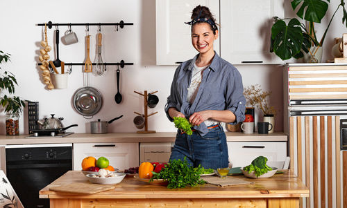 Young and beautiful housewife woman cooking in a white kitchen