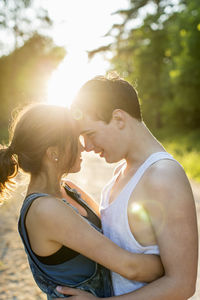 Couple looking at each other white embracing against bright sun