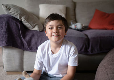 Portrait of smiling boy sitting on sofa at home