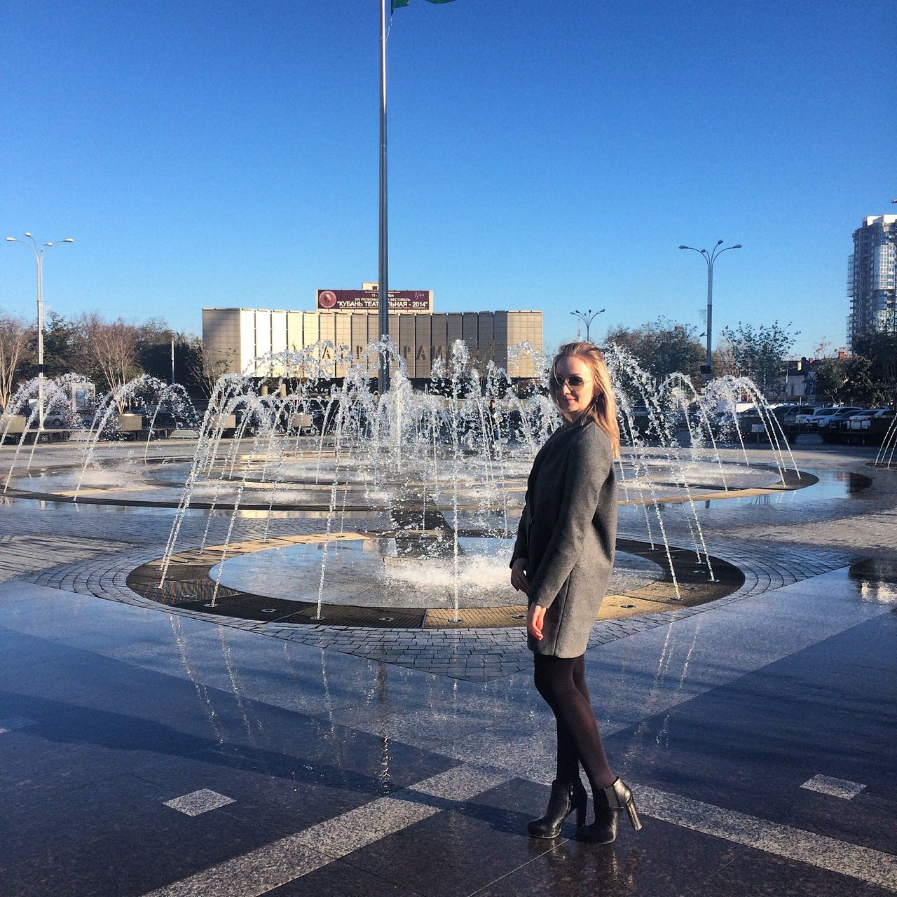 lifestyles, full length, leisure activity, clear sky, water, casual clothing, building exterior, standing, young adult, city, built structure, architecture, street, person, sunlight, front view, city life, young women