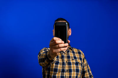 Low angle view of man using smart phone against blue background