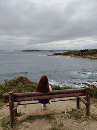 Bench by sea against sky