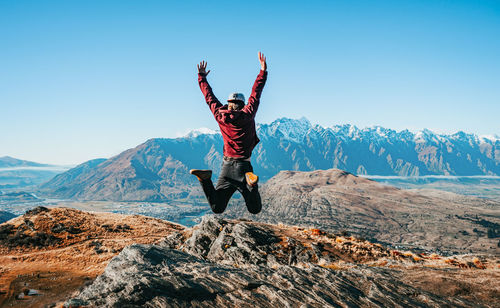 Man with arms raised in mountains against sky