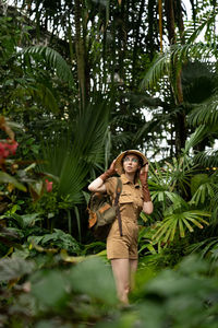 Woman standing by tree against plants