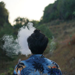 Rear view of man smoking outdoors