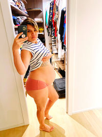 Young woman looking away while standing on floor at home