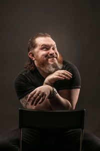 Man sitting on chair against black background