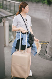 Tourist with luggage standing on footpath in city