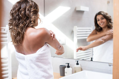 Rear view of woman standing in bathroom