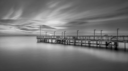 Pier over sea against sky in black and white 