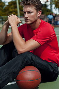 Young man with ball sitting on bench