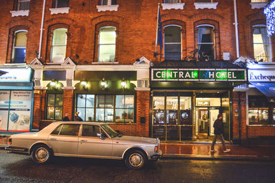 Cars on street against illuminated buildings in city