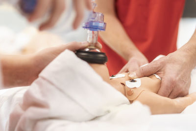 Hands of paramedic of emergency service during training resuscitation training on newborn dummy.