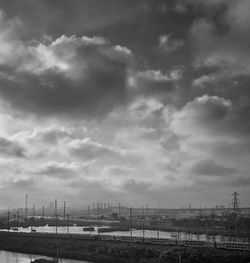 Distant view of city buildings against cloudy sky