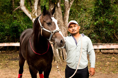 Portrait of man with horse standing outdoors