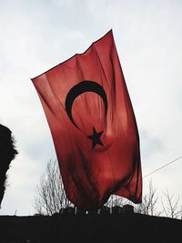 Low angle view of red flag against sky