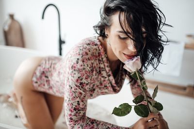 Woman holding rose in bathroom