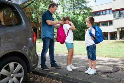 Dad sees off, gathers the children  to school, helps to put on a backpack. back to school