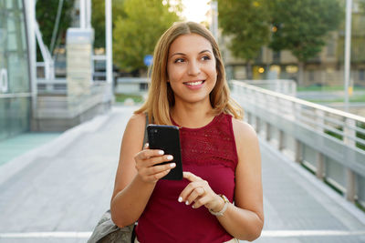 Smiling young woman looking away using mobile phone