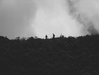 Silhouette people standing on landscape against sky