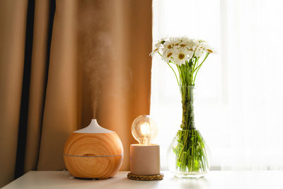 Aromatherapy concept. aroma oil diffuser on the table against the window.