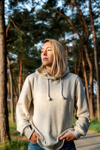 Portrait of a young blond woman walking in a pine forest at dawn.