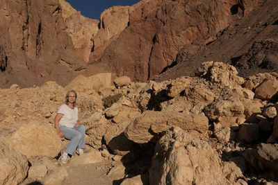 Senior woman sitting on rock against mountains