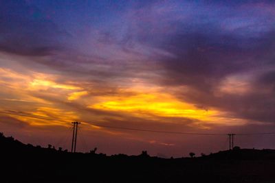 Silhouette electricity pylon against sky during sunset