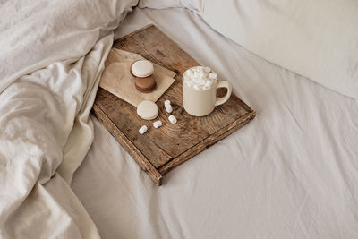 Coffee with marshmallows and macaroons on a wooden tray, in bed. aesthetically beautiful frame. 