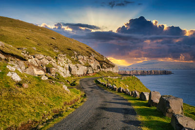 Road by sea against sky during sunset in faroe islands 