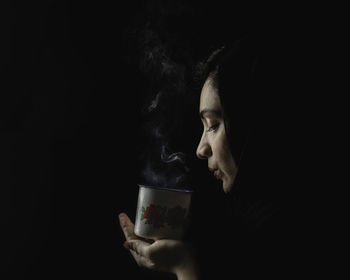 Portrait of man holding camera against black background