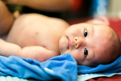 Close-up of baby boy lying down on soft blue towel