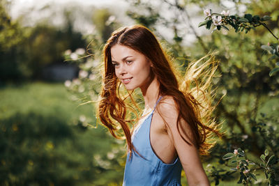 Young woman standing against plants