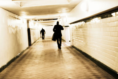 Rear view of men walking in tunnel