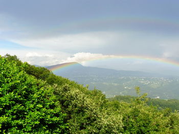 Rainbow over mountains against cloudy sky