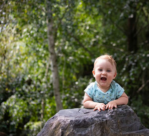 Portrait of cute girl sitting against trees