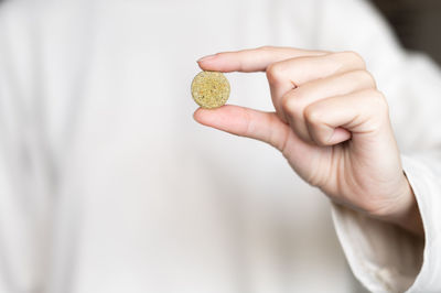 Close-up of a woman holding a pill, a herbal capsule in her hand against the background of a white
