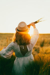 Rear view of woman on field against sky during sunset