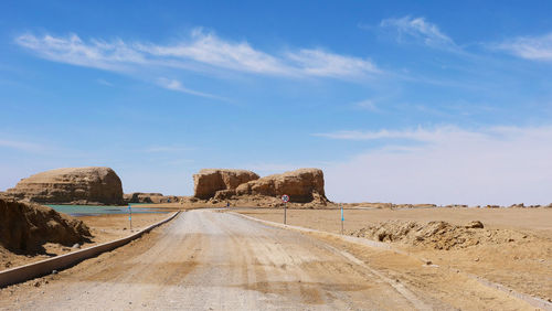 Road leading towards desert against sky