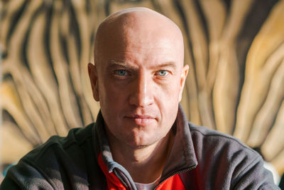 Close-up portrait of a bald man with blue eyes in a sports sweatshirt looks