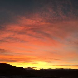 Silhouette landscape against dramatic sky during sunset