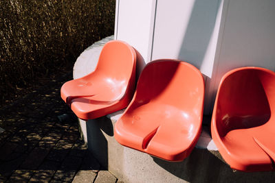 Three red plastic chairs side by side outdoors