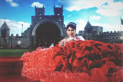 Portrait of woman against red building against sky