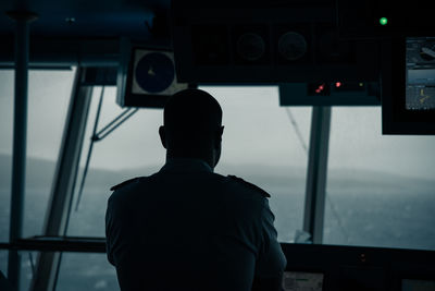 Rear view of man looking through window