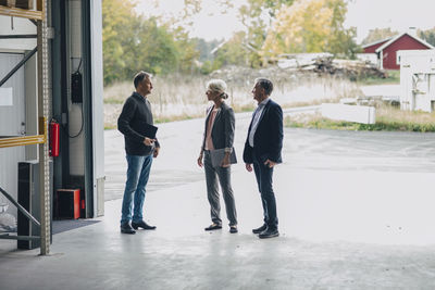 Business people discussing while standing at entrance of lumber industry